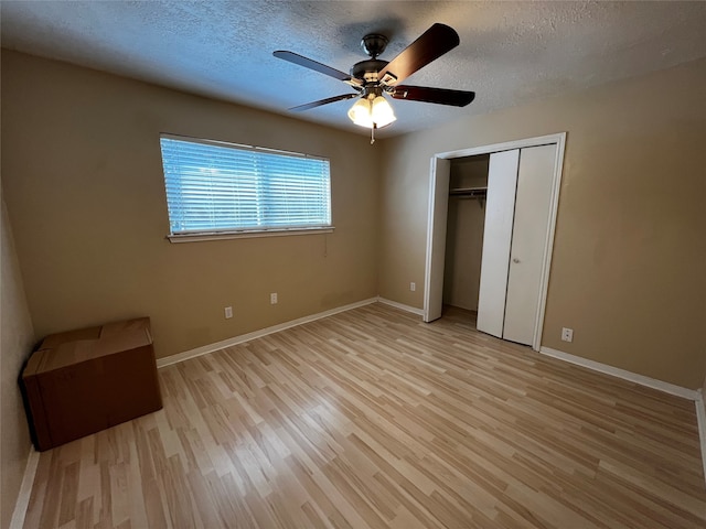 unfurnished bedroom featuring ceiling fan, light wood-type flooring, a textured ceiling, and a closet