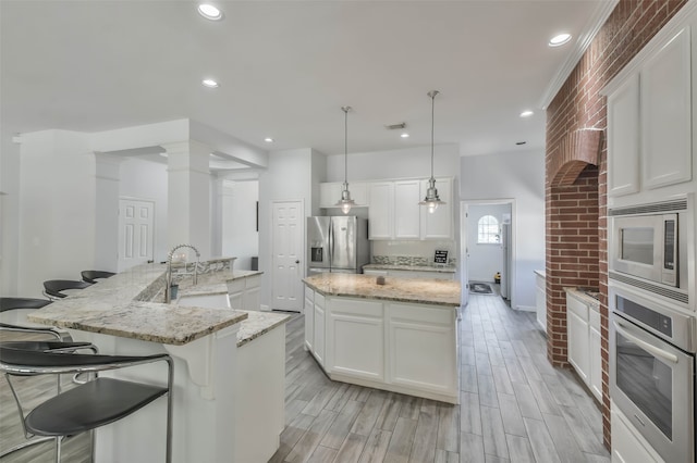 kitchen featuring stainless steel appliances, a large island with sink, and white cabinetry