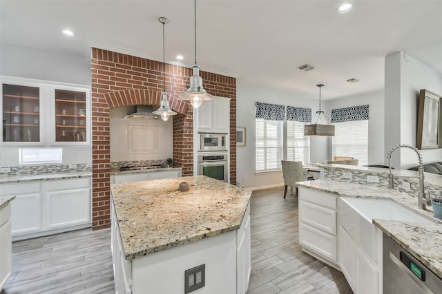 kitchen featuring stainless steel appliances, pendant lighting, white cabinets, and a kitchen island