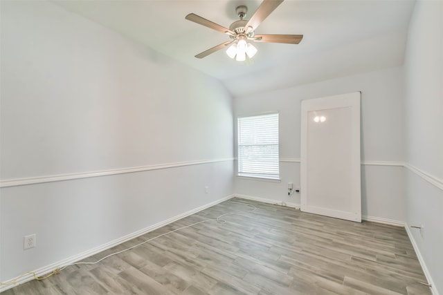 spare room with vaulted ceiling, light wood-type flooring, and ceiling fan