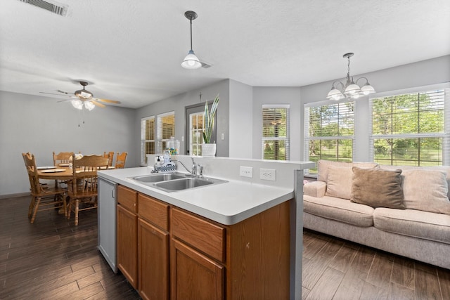 kitchen featuring sink, dark wood-type flooring, a kitchen island with sink, and pendant lighting