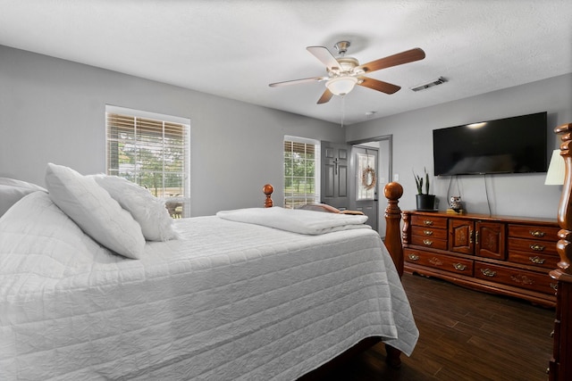 bedroom featuring dark hardwood / wood-style flooring, ceiling fan, and a textured ceiling