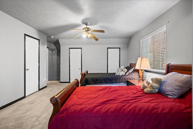 carpeted bedroom with multiple closets, ceiling fan, and a textured ceiling