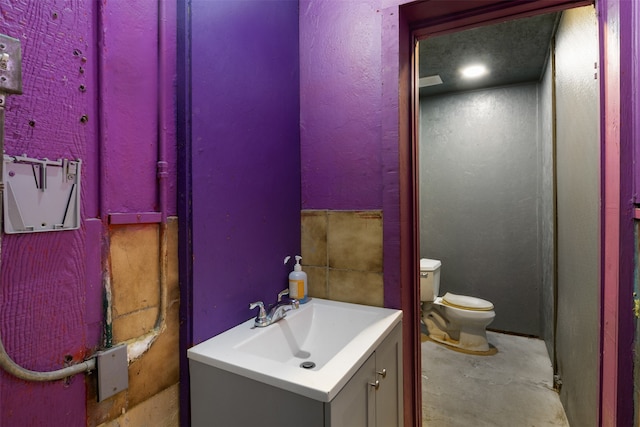 bathroom featuring concrete floors, toilet, and vanity