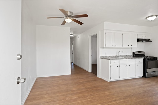 kitchen featuring stainless steel gas stove, white cabinetry, light hardwood / wood-style flooring, light stone counters, and ceiling fan