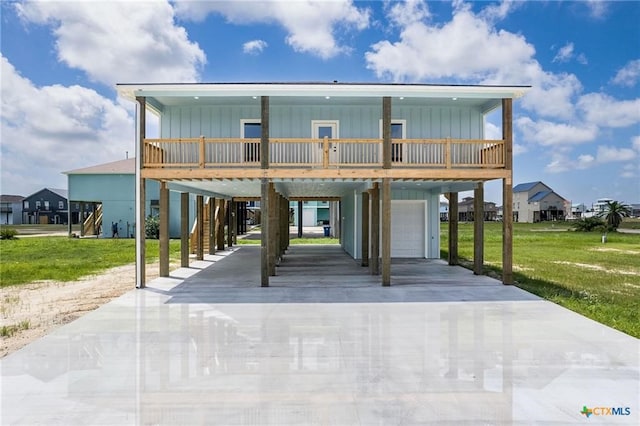 raised beach house featuring a front lawn, a carport, and a garage