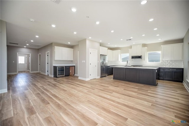 kitchen featuring light wood-type flooring, wine cooler, stainless steel appliances, and white cabinetry