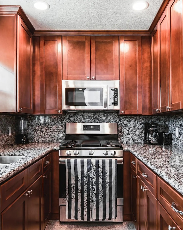 kitchen featuring decorative backsplash, stone counters, stainless steel appliances, and a textured ceiling