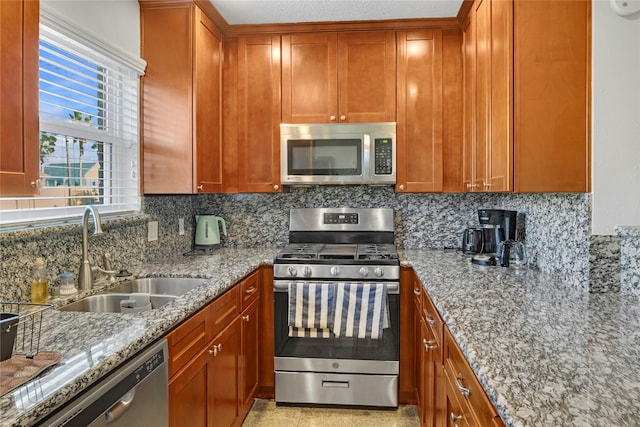 kitchen featuring light stone countertops, backsplash, stainless steel appliances, and sink