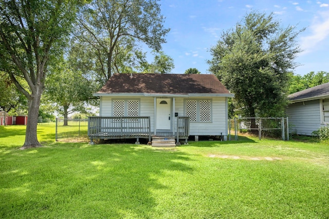 rear view of house featuring fence, a deck, and a lawn