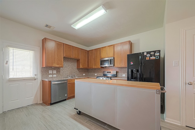 kitchen featuring backsplash, sink, stainless steel appliances, and a kitchen island