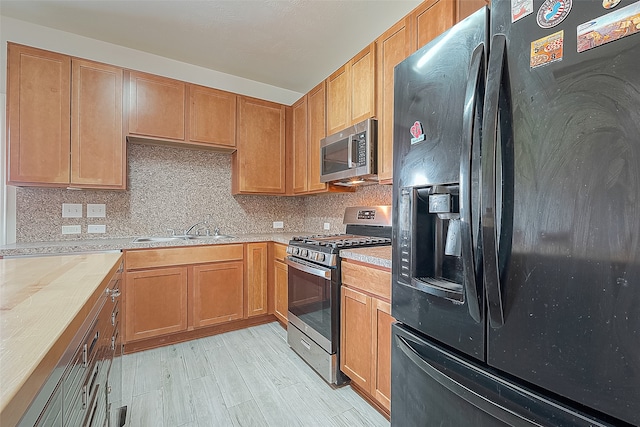 kitchen with appliances with stainless steel finishes, light hardwood / wood-style floors, decorative backsplash, and sink