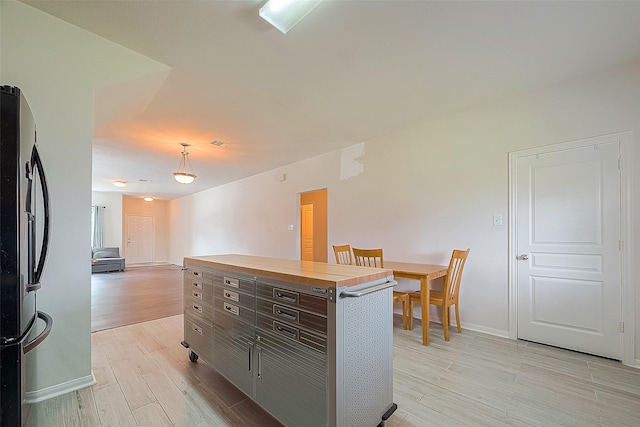 kitchen with light wood-type flooring, dark brown cabinetry, and stainless steel fridge