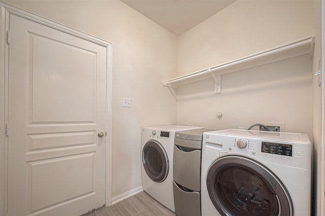 laundry area with light hardwood / wood-style flooring and washing machine and dryer