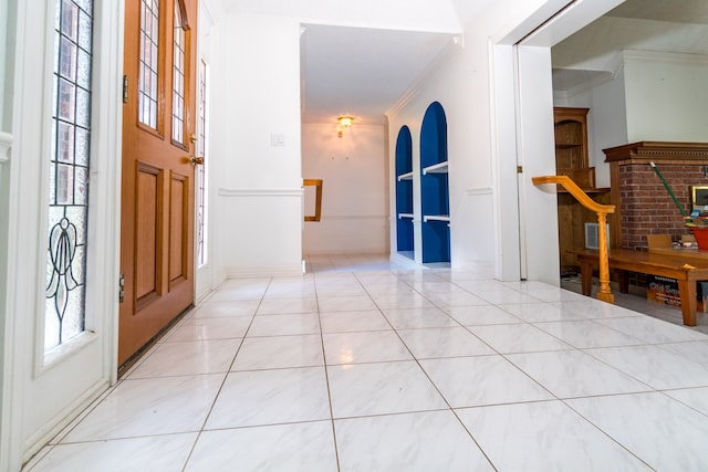 foyer entrance with crown molding and light tile patterned floors