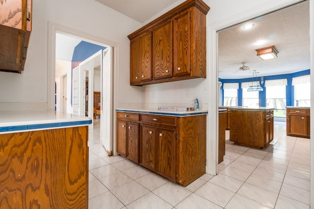 kitchen with ceiling fan, decorative light fixtures, a textured ceiling, and light tile patterned floors