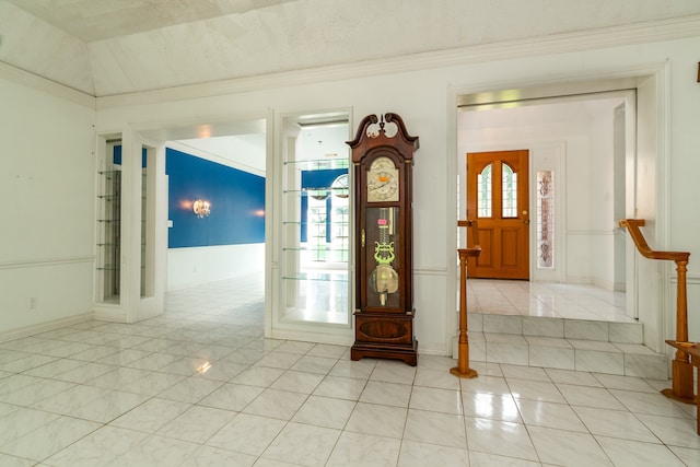 tiled entryway with ornamental molding and a textured ceiling