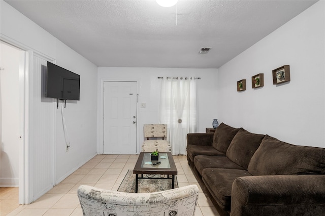 living room with visible vents, a textured ceiling, and light tile patterned floors