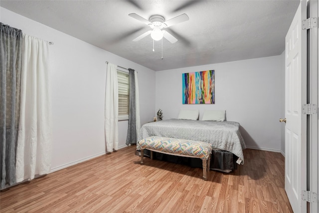 bedroom with light wood-style flooring, baseboards, ceiling fan, and a textured ceiling