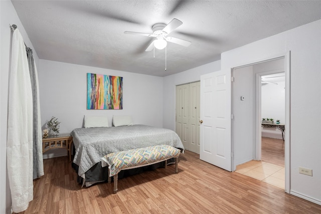 bedroom featuring a textured ceiling, ceiling fan, a closet, and light wood-style floors