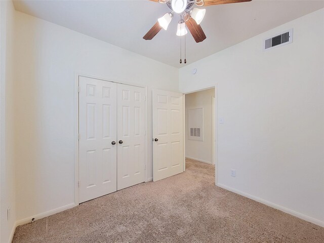 unfurnished bedroom with ceiling fan, light carpet, and a closet