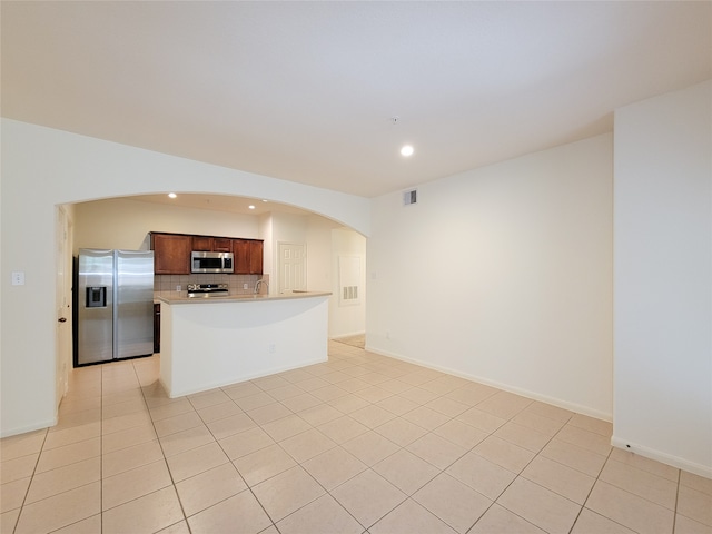 kitchen with backsplash, stainless steel appliances, a center island, and light tile patterned floors