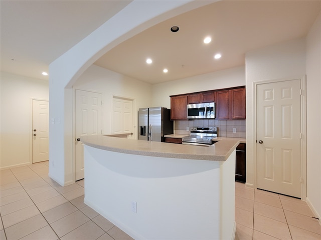 kitchen with light tile patterned floors, appliances with stainless steel finishes, tasteful backsplash, and a kitchen island