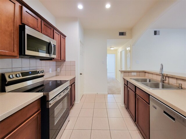 kitchen with sink, stainless steel appliances, decorative backsplash, and light carpet