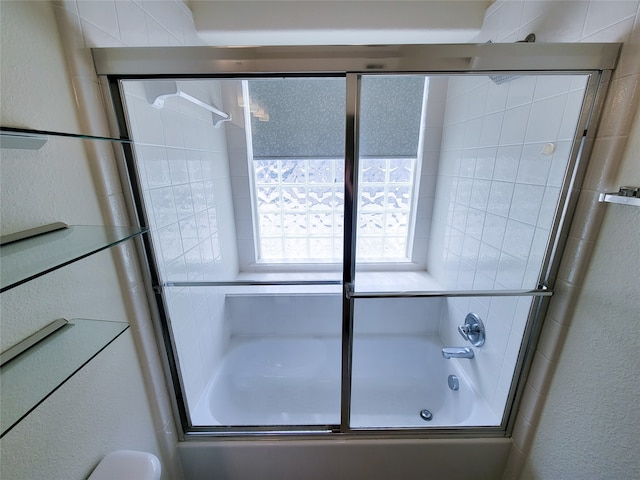 bathroom featuring toilet and combined bath / shower with glass door