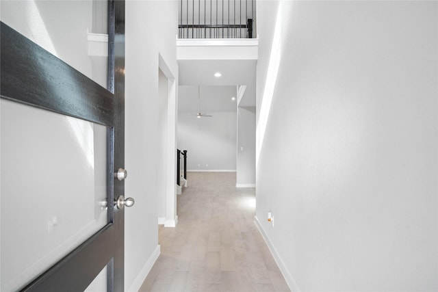 corridor featuring a towering ceiling and light hardwood / wood-style flooring