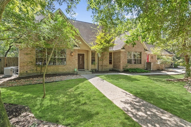 view of front of house with roof with shingles, fence, a front lawn, and brick siding