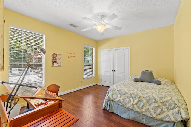 bedroom with a textured ceiling, a closet, ceiling fan, and dark hardwood / wood-style floors