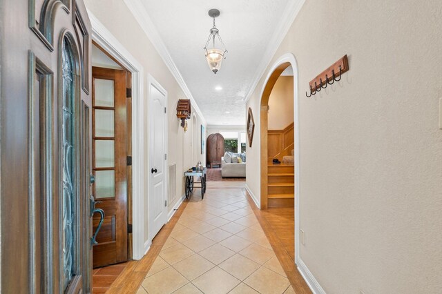 hallway featuring ornamental molding and light tile patterned floors