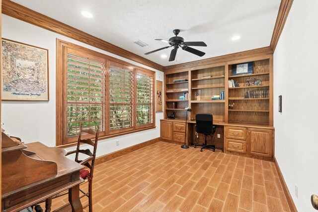 office area with built in features, crown molding, a textured ceiling, built in desk, and ceiling fan