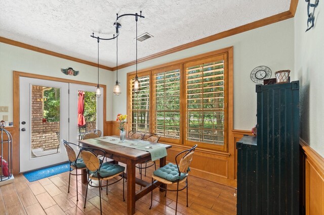 dining area featuring light wood-type flooring, a textured ceiling, and ornamental molding