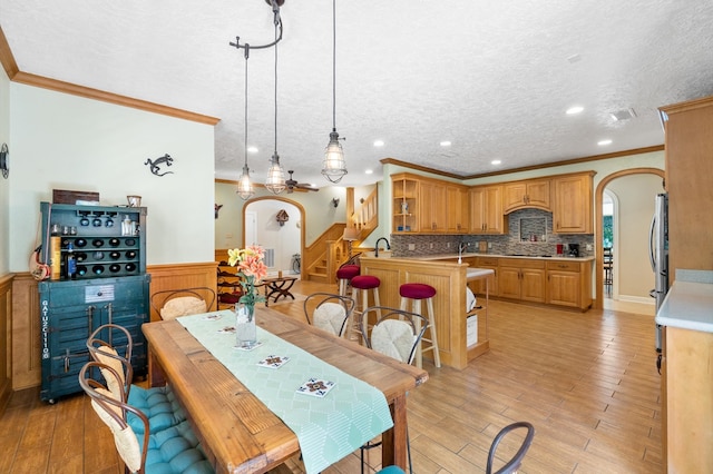 dining room featuring ceiling fan, light hardwood / wood-style floors, sink, a textured ceiling, and crown molding