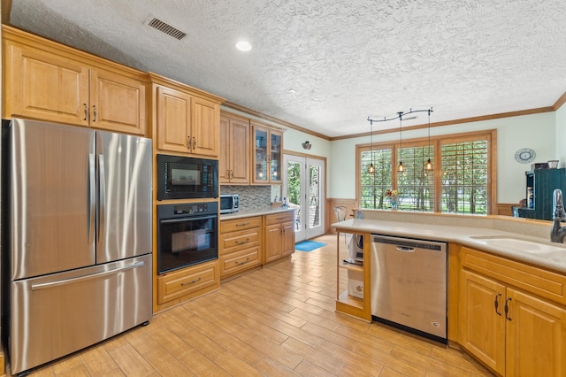 kitchen featuring sink, crown molding, black appliances, light wood-type flooring, and a textured ceiling