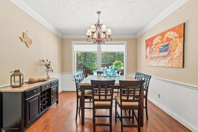 dining room with a textured ceiling, ornamental molding, a chandelier, and dark hardwood / wood-style flooring