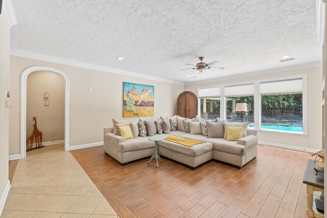 tiled living room featuring ceiling fan, a textured ceiling, and ornamental molding