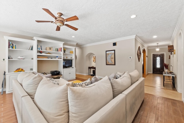 tiled living room featuring ceiling fan, a textured ceiling, and ornamental molding