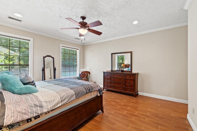 bedroom with ceiling fan, light wood-type flooring, a textured ceiling, and crown molding