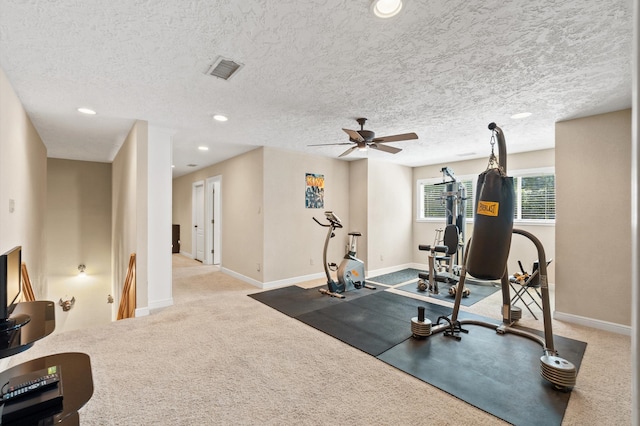 exercise room featuring a textured ceiling, ceiling fan, and light colored carpet