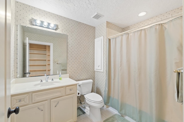 bathroom with tile patterned flooring, toilet, a textured ceiling, and vanity