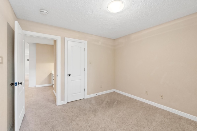 unfurnished room featuring a textured ceiling and light carpet