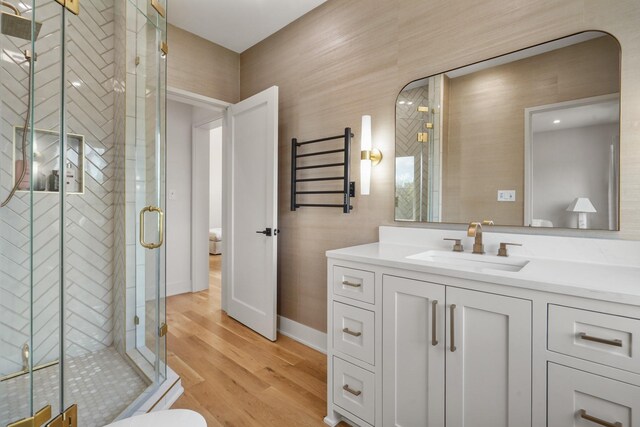 bathroom with an enclosed shower, vanity, hardwood / wood-style floors, and toilet