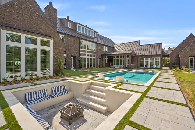 view of swimming pool featuring a patio and a fire pit