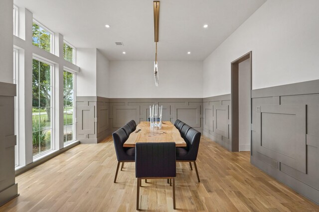 dining room with light hardwood / wood-style flooring, a healthy amount of sunlight, and a towering ceiling