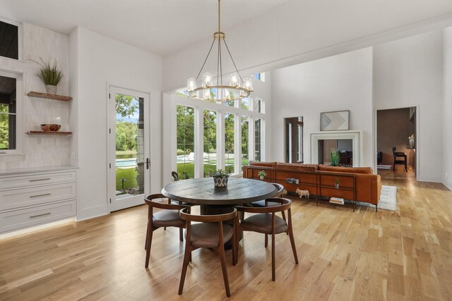 dining area with light hardwood / wood-style floors, a high ceiling, and a notable chandelier