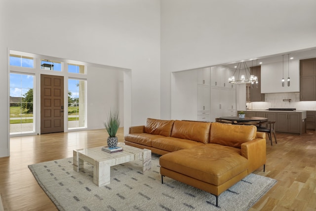 living room featuring a towering ceiling, an inviting chandelier, and light hardwood / wood-style floors