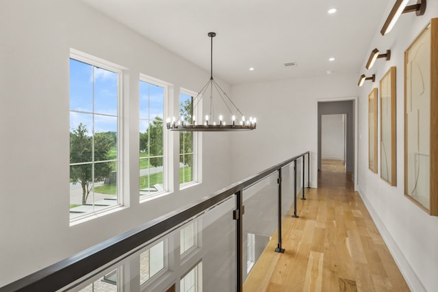 hall with an inviting chandelier and light wood-type flooring